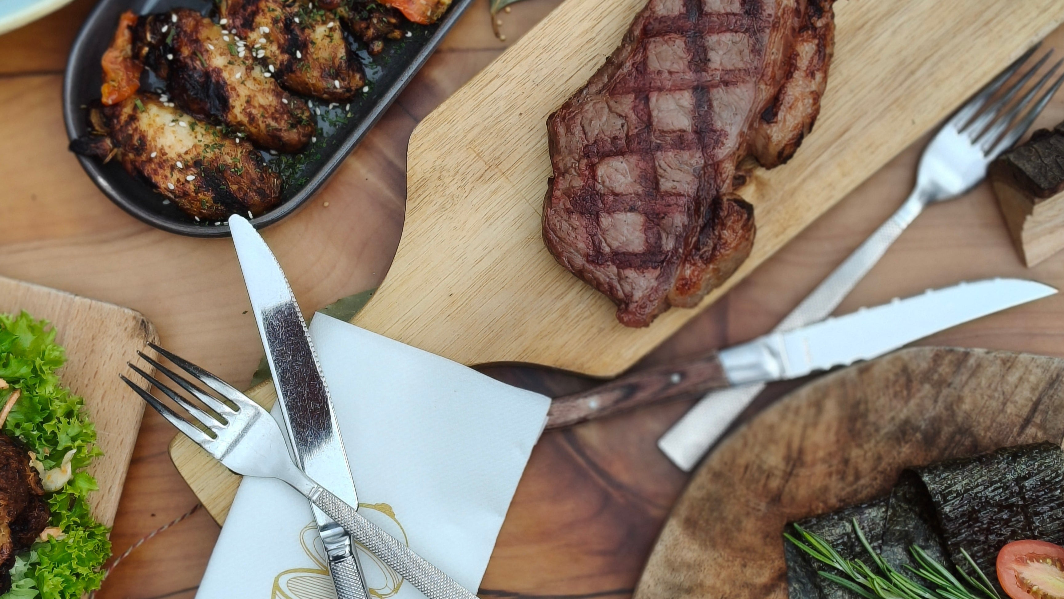 Gegrilde biefstuk op een houten snijplank met keukengerei en bijgerechten. van that chef aan huis 